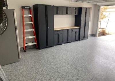 A garage with black cabinets and a ladder.